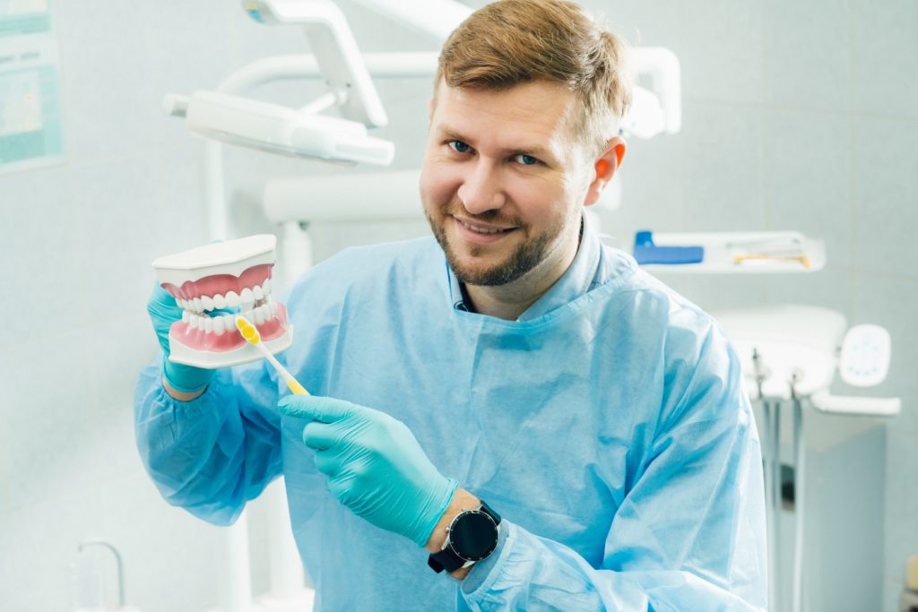 dentist demonstrating how to brush teeth