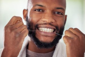 black man flossing his teeth for good oral health as a new year's resolution