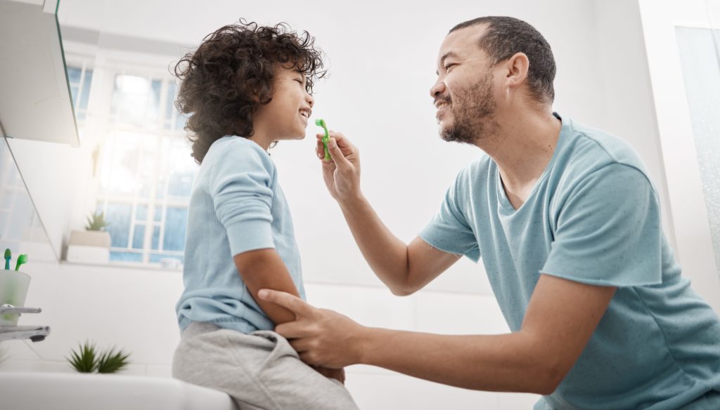father teaching child to look after his child's oral health