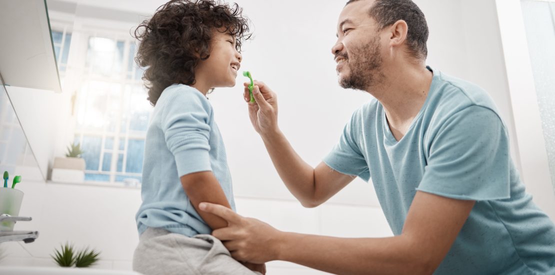 father teaching child to look after his child's oral health