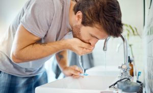 man rinsing his mouth after brushing his teeth to prevent dental problems