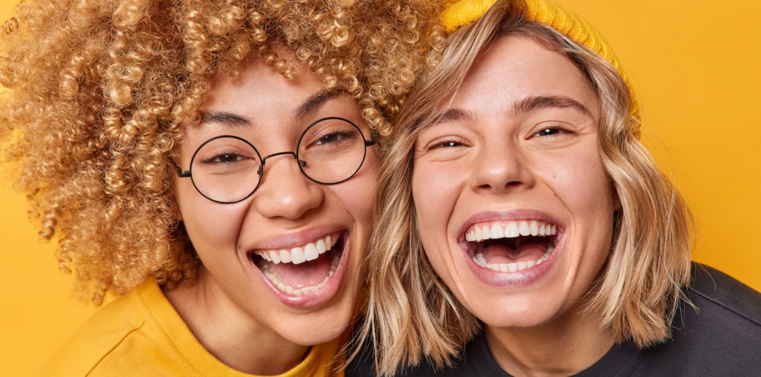 happy carefree friendly female models laugh joyfully stand each other smile toothily have upbeat mood isolated yellow background people friendship positive emotions concept